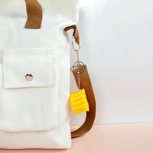 Realistic PVC corn keychain hanging on a white canvas bag with silver metal chain