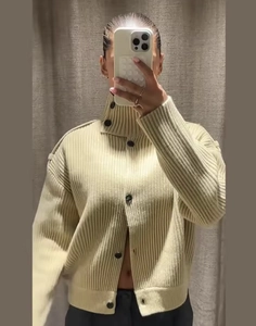 Detail view of beige ribbed knit cardigan with high neck collar and dark buttons