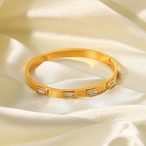Détail d'un bracelet en acier titane doré avec des cristaux rectangulaires sur soie