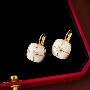 Close-up of vintage square gold-plated earrings with zircon in a luxury red jewelry box