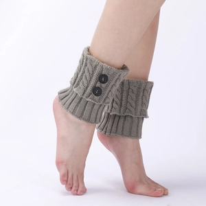 Detail of grey cable-knit leg warmers featuring decorative black buttons on the side