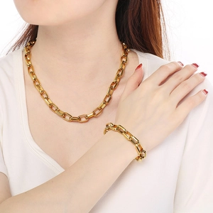 Close-up of a gold geometric Cuban link chain necklace and bracelet set on a model