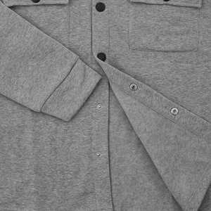 Macro view of metallic snap button closure and grey knit fabric on a men's casual jacket