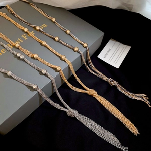 Detailed view of layered tassel necklaces in gold, silver, and gunmetal finishes on velvet