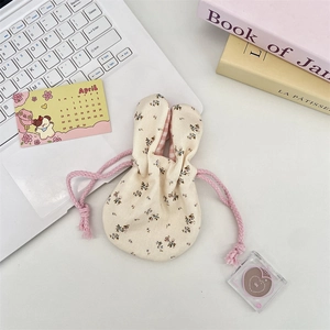 Detail of floral drawstring pouch with bunny ears and pink checkered lining on a desk