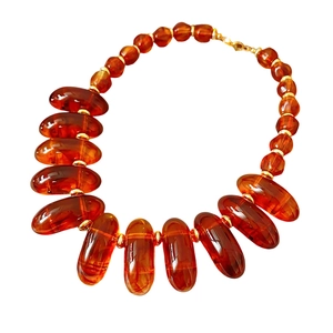 Irregular amber geometric beaded necklace with gold rings on white background
