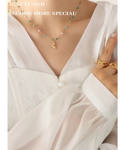 Detail of tulip pendant necklace with green beads and gold ring set on a model