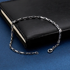 Macro shot of silver stainless steel square link chain bracelet with lobster clasp detail