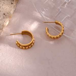Macro view showing the wave-edge texture and golden metal finish on C-shape hoop earrings