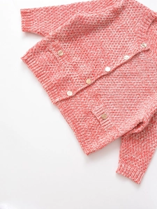 Detail of red and white knit cardigan showing thick texture and gold button accents