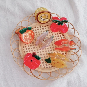 Chic fruit-shaped hair clips including cherry and strawberry on a rustic tray
