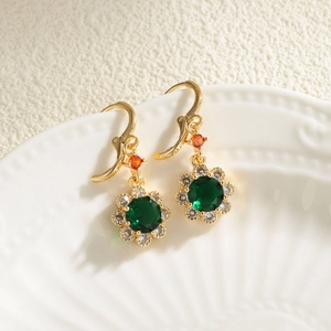 Close-up of 18K gold flower earrings featuring green crystal and orange zircon accents