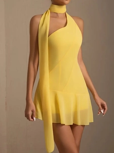 Détail d'une mini robe en mousseline jaune avec col licou et ourlet à volants