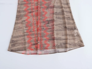 Détail de l'ourlet de la robe avec tissu beige, rayures noires et motifs zigzag rouges