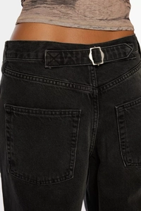 Detailed macro view of back waist adjustment buckle and pocket on black wide-leg jeans