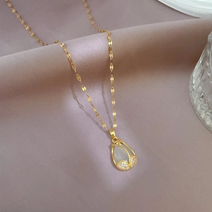 Detail of gold tulip pendant with cat eye stone and pavé zircons on soft fabric