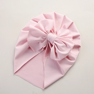 Detailed close-up of pink waffle texture baby turban hat with large decorative bow