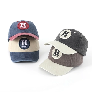 Detail of washed cotton baseball caps with Happy embroidery in four vintage colors