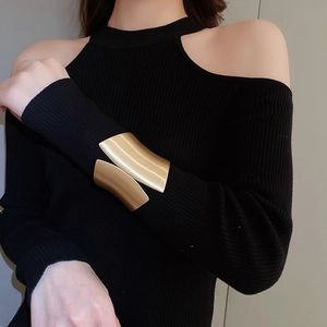 Close-up of wide brushed gold irregular metal cuff bracelet worn over black sleeve
