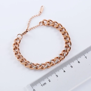 Rose gold Cuban chain bracelet with white diamonds on a minimalist flat lay background