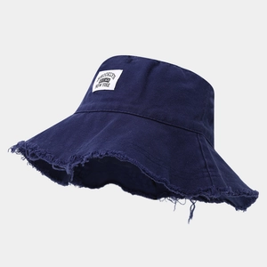 Dettaglio cappello bucket blu navy con bordi sfrangiati e toppa con logo Brooklyn