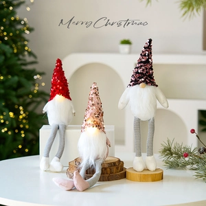 Three glowing Christmas gnomes with LED lights on a festive white table setup