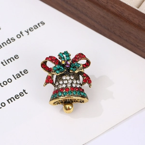 Detail of vintage gold Christmas bell brooch with red and green rhinestones on card