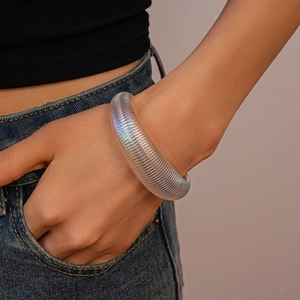 Detailed view of an iridescent acrylic wide bangle with sleek striped texture on model