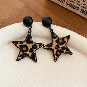 Détail macro de boucles d'oreilles étoile à motif léopard sur un plateau décoratif