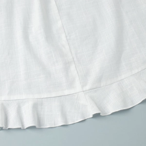 Detailed macro view of white cotton linen fabric texture and ruffled hem stitching