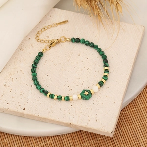 Bracelet de perles de malachite verte avec étoiles dorées sur socle pierre