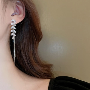 Detail of elegant leaf earrings with silver tassels and zircon stones worn on model