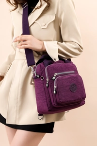 Détail du sac bandoulière violet en nylon avec poches porté avec un manteau beige