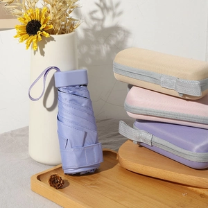 Portable purple mini capsule umbrella with matte storage cases on a wooden tray