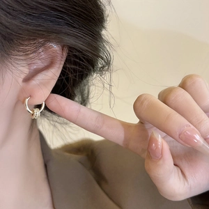 Detail of 18k gold plated hoop earring with sparkling zircon pendant on ear