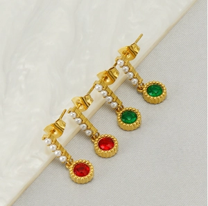 Detailed macro view of vintage oval pearl earrings with red and green gemstones in gold