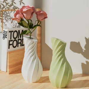 Detailed view of matte spiral vases in white and green with modern 3D striped texture