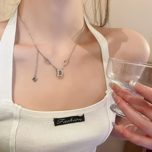 Close-up of a silver D-letter necklace with star pendant worn on a collarbone