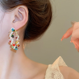 Close-up of pearl and colorful crystal woven hoop earrings on model for a sweet look