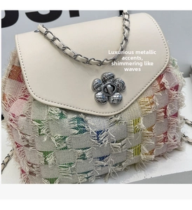 Detail of silver floral metal clasp and woven texture on a stylish denim backpack