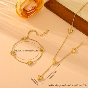 Parure bijoux en acier titane avec collier et bracelet à pampilles cœur sur fond pêche