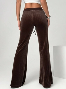 Detail of high-waist brown velvet flared trousers showing fabric sheen and drape