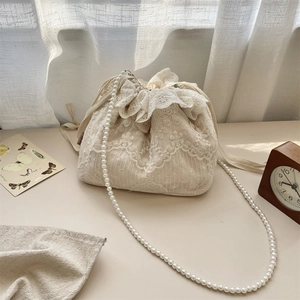 Detailansicht der cremefarbenen Spitzenbeuteltasche mit Kordelzug und Perlenkette