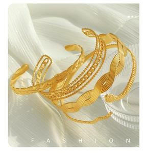 Close-up of assorted 18K gold plated Cuban chain bracelets on elegant white silk fabric