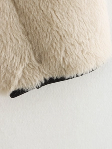 Dettaglio della texture in pelliccia sintetica beige con bordo nero a contrasto