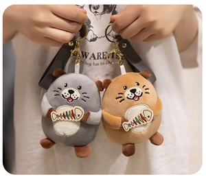 Close-up of cute plush sea otter keychains with colorful fish bone embroidery and golden clips