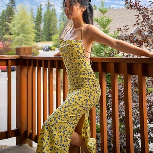 Detail of floral yellow maxi dress with side slit and backless design in summer sunlight