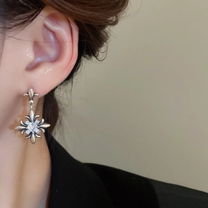 Detail of vintage silver fleur-de-lis earrings with zircon stones worn by a model