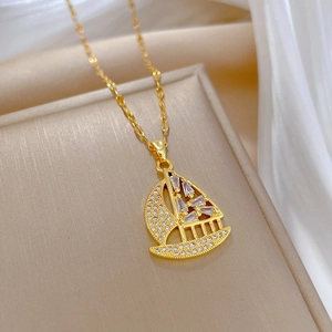 Elegant gold sailboat pendant necklace with zircon stones on soft silk background