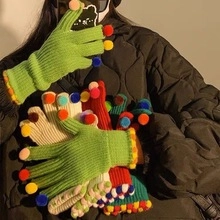 Close-up of colorful knitted gloves with fluffy pompoms for kids winter fashion